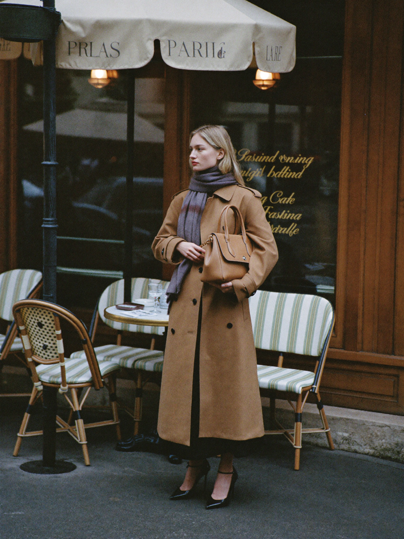 Woman in camel trench outside Parisian cafe